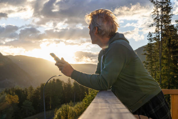 istock Mature man relaxes on house deck with mobile phone 2177305005