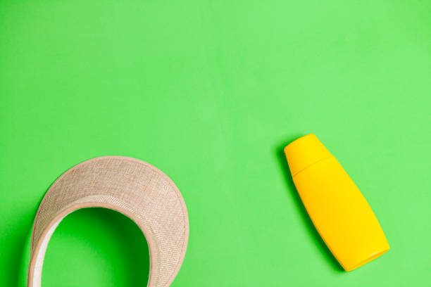 istock Jar of yellow sunscreen and visor on green background. 2177305050