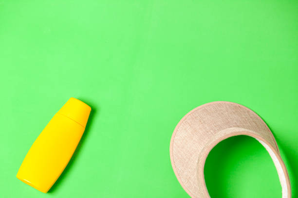istock Jar of yellow sunscreen and visor on green background. 2177305064