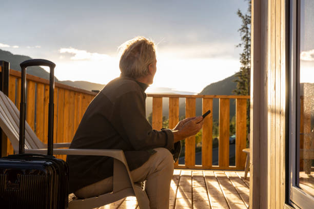 istock Mature man uses mobile phone on porch at sunrise 2177305321