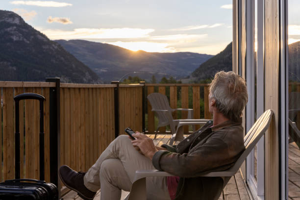 istock Mature man uses mobile phone on porch at sunrise 2177305465