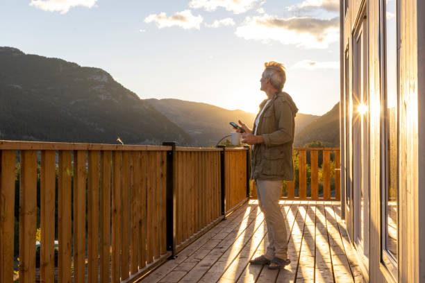 istock Mature man relaxes on house deck with mobile phone 2177305840