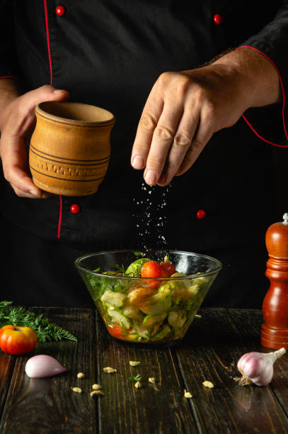 istock A cook at the kitchen table prepares a vegetable mix for breakfast. The chef adds salt to a vegetable salad with his hands. Vegetable diet concept for a restaurant 2177309243
