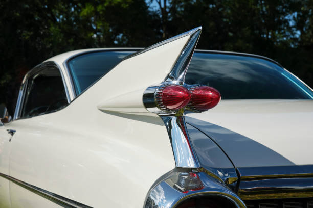 White classic American oldtimer car with red tail lights on its large tail fin and chrome elements.