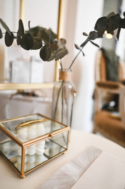 Stock photo features a large ceramic table lamp with an oversized beige and brown lampshade, acting as a bold statement piece. Surrounded by house plants and elegant candle sticks, it enhances a modern, stylish interior