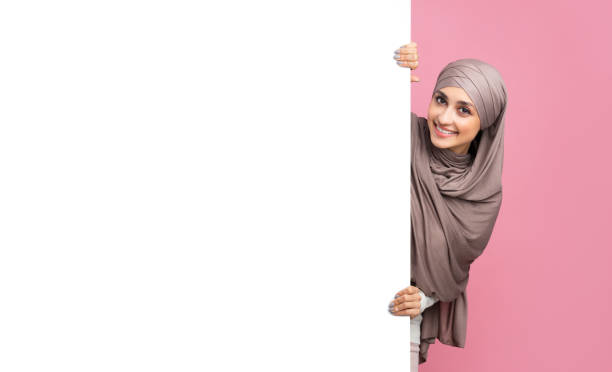 istock Beautiful arabic woman in hijab standing next to white advertisement board 2177321777