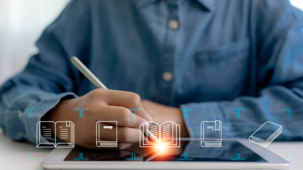 istock E-library concept. A Man uses a tablet with virtual E-book icons for electronic books online, knowledge base on the internet, digital library, or e-library. 2177324670