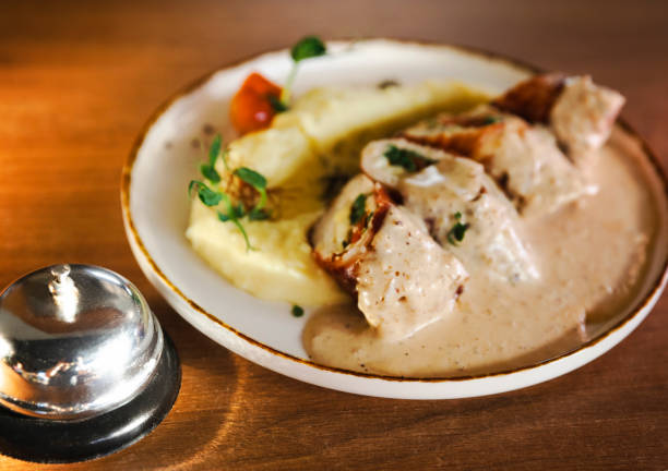 Appetizing chicken roulade served with creamy mashed potatoes and garnished with fresh herbs, presented on a white plate. Perfect for gourmet food lovers and elegant dining experiences.