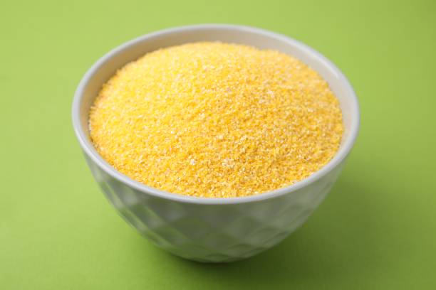 istock Raw cornmeal in bowl on green table, closeup 2177325254