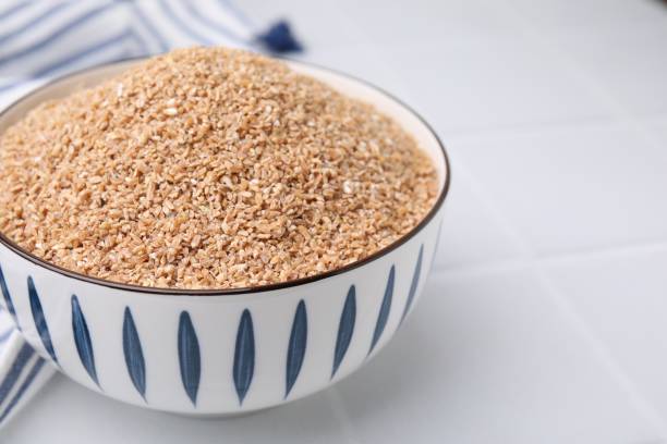 istock Dry wheat groats in bowl on white table, closeup. Space for text 2177325272