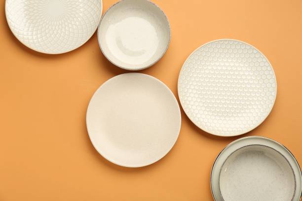 istock Beautiful beige ceramic plates on orange background, flat lay 2177326536