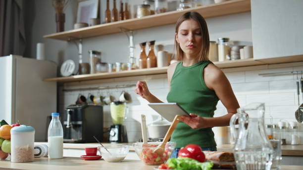 istock Woman using tablet kitchen going cooking at morning. Girl looking video recipe 2177326542