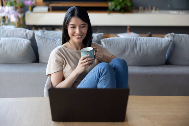 istock Happy woman watching videos on her laptop while drinking coffee 2177327270