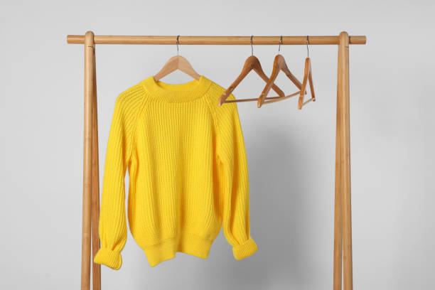 istock Rack with yellow knitted sweater and hangers on light background 2177329062