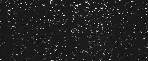 istock Atmospheric minimal grayscale backdrop with rain droplets on glass. Wet window with rainy drops and dirt spots closeup. Blurry minimalist monochrome background of dirty window glass with raindrops. 2177332983