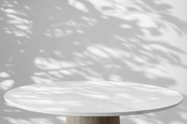Round marble table top with tree leaves shadow drop on white wall background for mockup product display