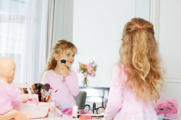 istock Little girl plays with makeup, smiling at reflection in mirror 2177333520
