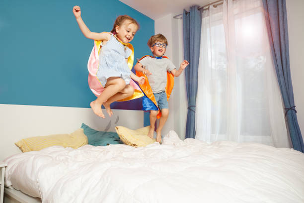 istock Children in vibrant superhero capes happily springing on a bed 2177333654