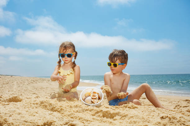 istock Siblings gathering seashells in bucket on the summer beach sun 2177333973