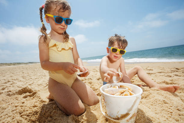 istock Kids enjoying a sunny day at sandy beach, playing with shells 2177334023