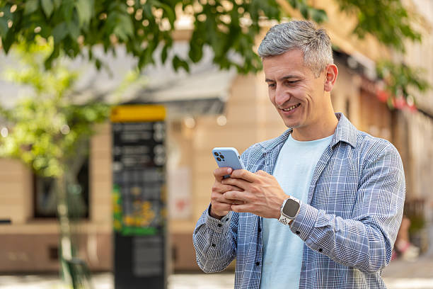 istock Happy Caucasian man using smartphone typing text messages browsing internet standing on city street 2177334109