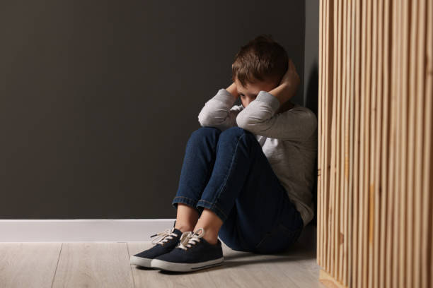istock Upset boy sitting on floor near gray wall indoors, space for text 2177334773