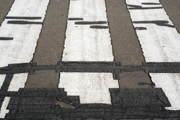 Close-up on part of an old zebra pedestrian crossing in bad condition.