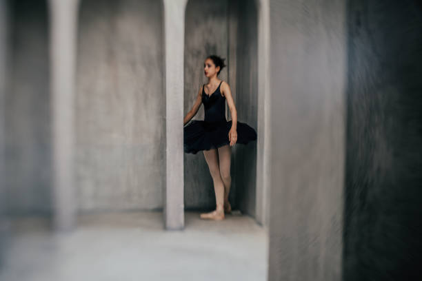 Young female ballet dancer dancing on tiptoes in rehearsal room at studio