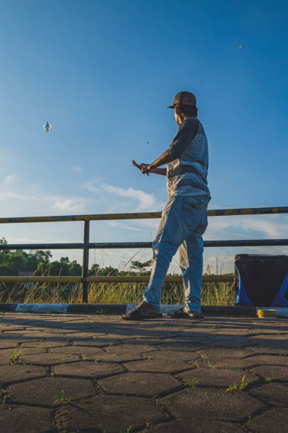 Balikpapan, Indonesia - June 27th, 2024. his hands expertly maneuvering the white kite into the golden sunlight.