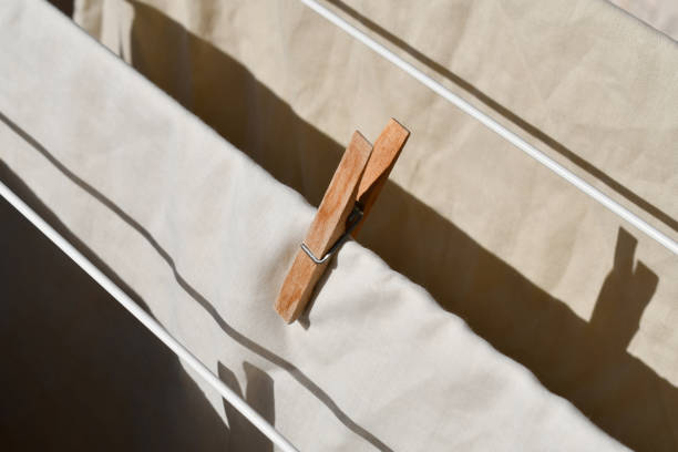 Clothes pegs or pins with clothes on clothes drying rack.\tHousework concept.