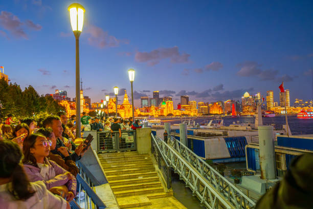 Shanghai, China - October 3rd 2024: tourists and locals take walking on The Bund at night, a scenic waterfront area in central Shanghai. It is one of the most famous tourist destinations in Shanghai and houses buildings of various architectures.
