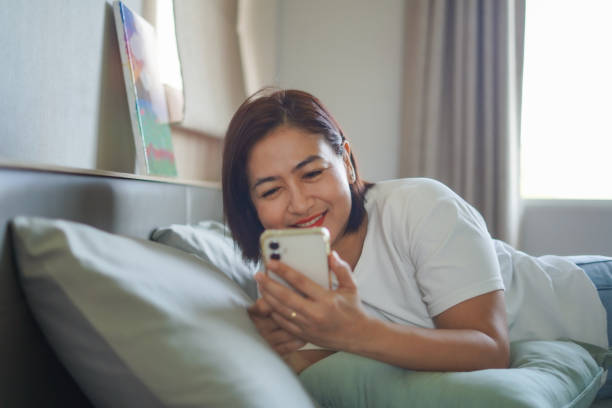 istock Woman lying on the bed playing mobile phone 2177351315