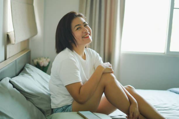 istock A woman sits and smiles on the bed. 2177351361