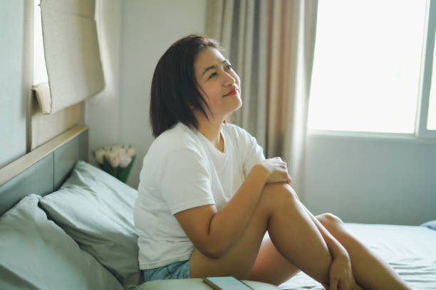 istock A woman sits and smiles on the bed. 2177351364