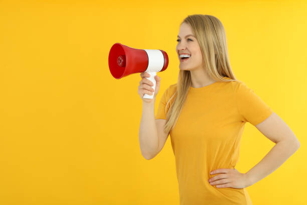 istock Young woman with megaphone on yellow background 2177354940