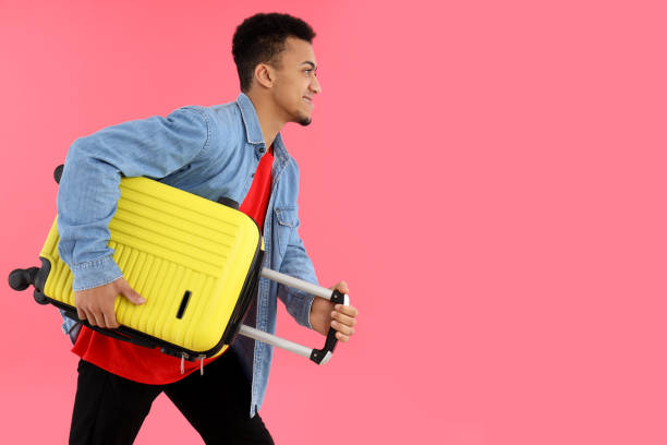 istock Young man with suitcase on pink background 2177361211