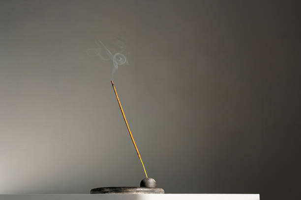 Burning incense stick and smoke with contrast shadows.