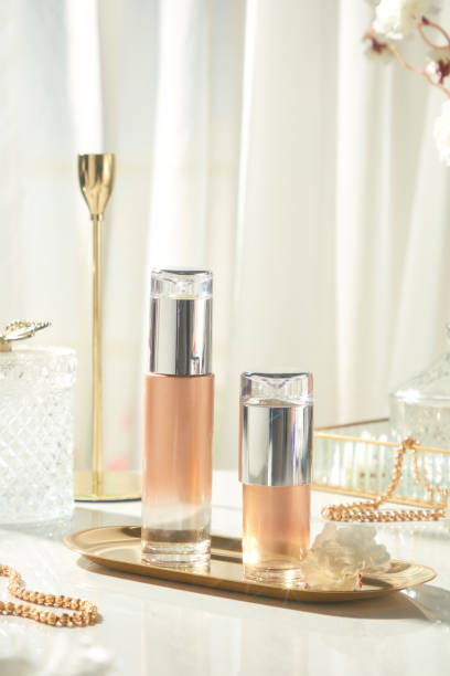 istock Two unlabeled lotion bottles sit on a long brass tray with white flowers, surrounded by glass boxes, jewelry, and gold-colored ornaments. Set against a luxurious backdrop of white silk. 2177369708