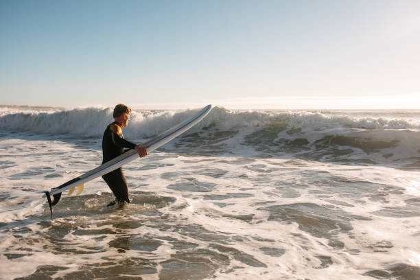 istock Surfer with board entering the water 2177372953