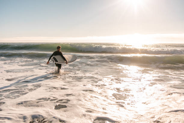 istock Surfer with surfboard entering the water 2177372963