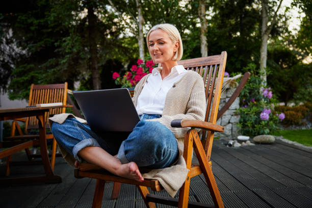 istock Mature woman outdoors using laptop in backyard patio 2177373120