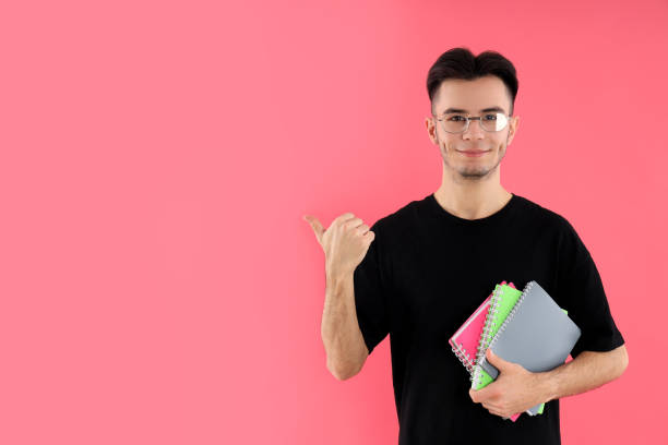 istock Male student with notebooks on pink background 2177375393
