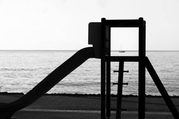 Slide on the beach with framed sailboat in the horizon