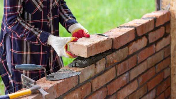 istock A young female bricklayer builds a wall, puts a brick on a cement mortar 2177380093