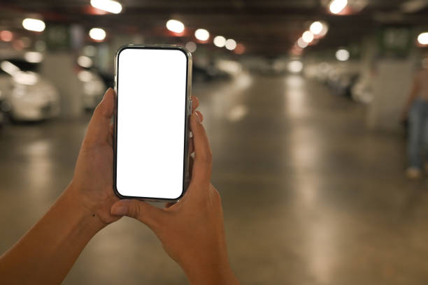 istock Hand holding smartphone with a blank white screen over blurred parking garage background 2177381274