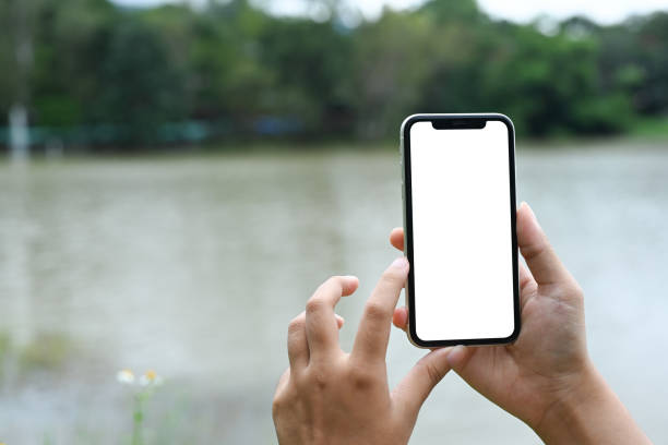 istock Hands holding mobile phone with blank screen against background scenery with lake 2177381413