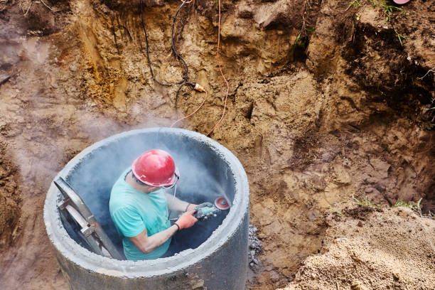 istock Worker makes hole for an inlet pipe in concrete septic tank ring using an abrasive wheel and an angle grinder. 2177384711