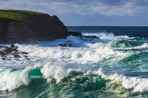 Large waves roll into the coastline from storm swell. Photographed along the south coast of NSW, Australia.