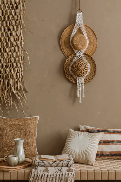 istock Interior design of elegant boho composition with mock up poster frame, modern beige sofa, brown pillow, elegant wooden stand, glass vase with dried flowers, patterned carpet, books and personal accessories. Home decor. Template. 2177389356