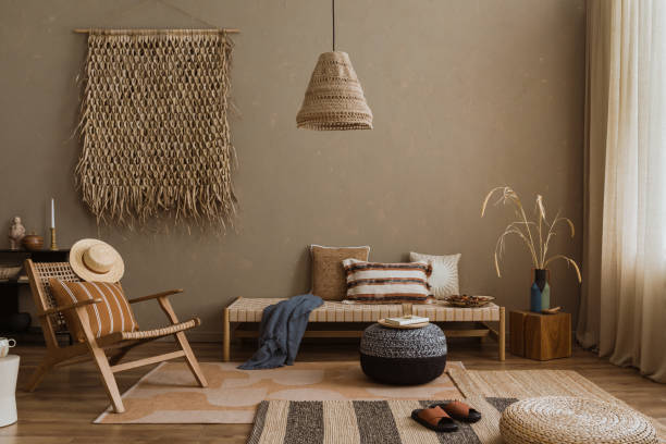 istock Interior design of elegant boho composition with mock up poster frame, modern beige sofa, brown pillow, elegant wooden stand, glass vase with dried flowers, patterned carpet, books and personal accessories. Home decor. Template. 2177389376